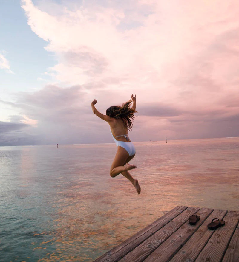 Woman Jumping on the sea with Reef Sandals